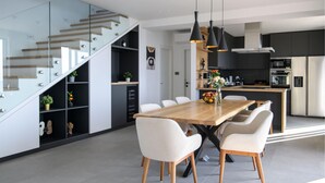 A modern kitchen with a central island, white chairs, and a wooden dining table.