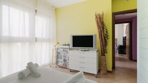Una habitación de hotel con cama, televisión, escritorio y planta.