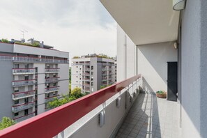 Ein Balkon mit roter Reling mit Blick auf eine Reihe moderner Wohngebäude.