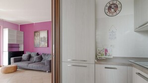 Una cocina moderna con armarios blancos, un reloj y un cuadro colgado en la pared.