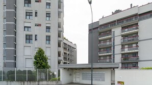 Un edificio residencial de varios pisos con balcones, una entrada porticada y una farola.
