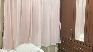 A bedroom with a bed, a wardrobe, and an air conditioning unit.