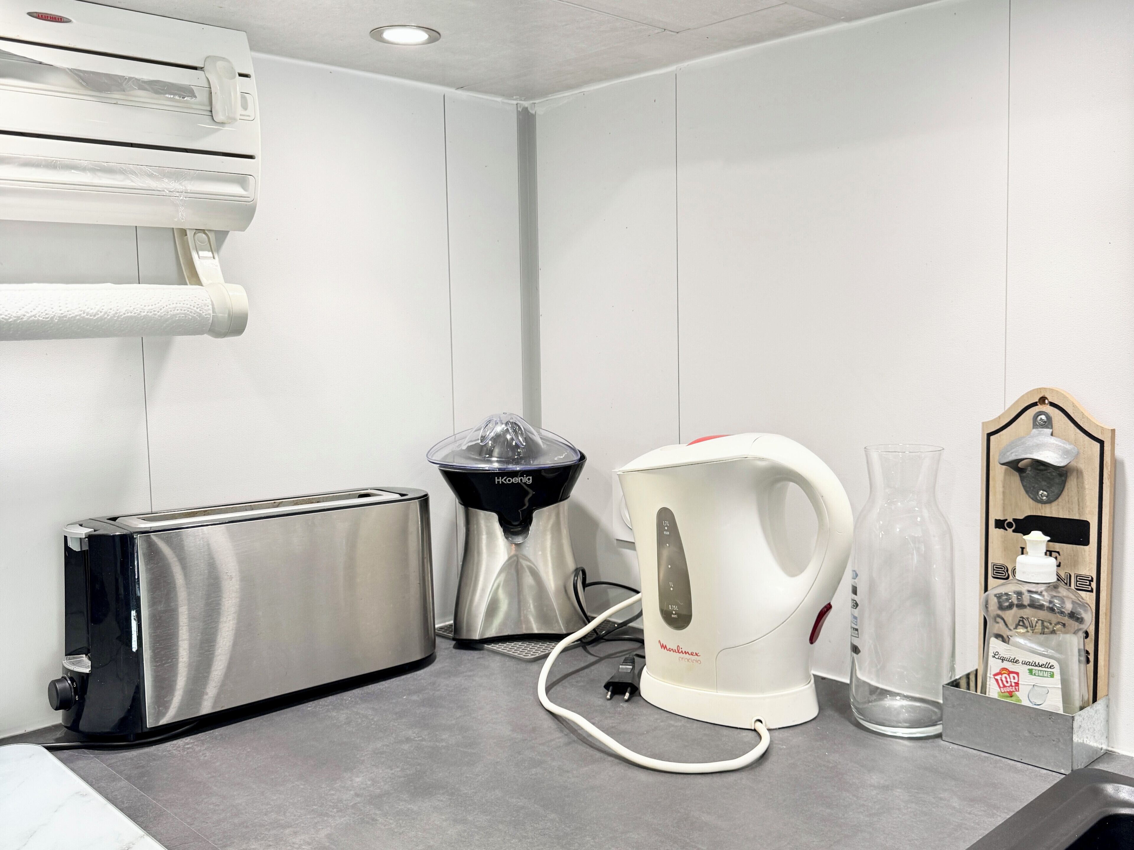 A kitchenette with a toaster, a coffee maker, and a kettle on a countertop.