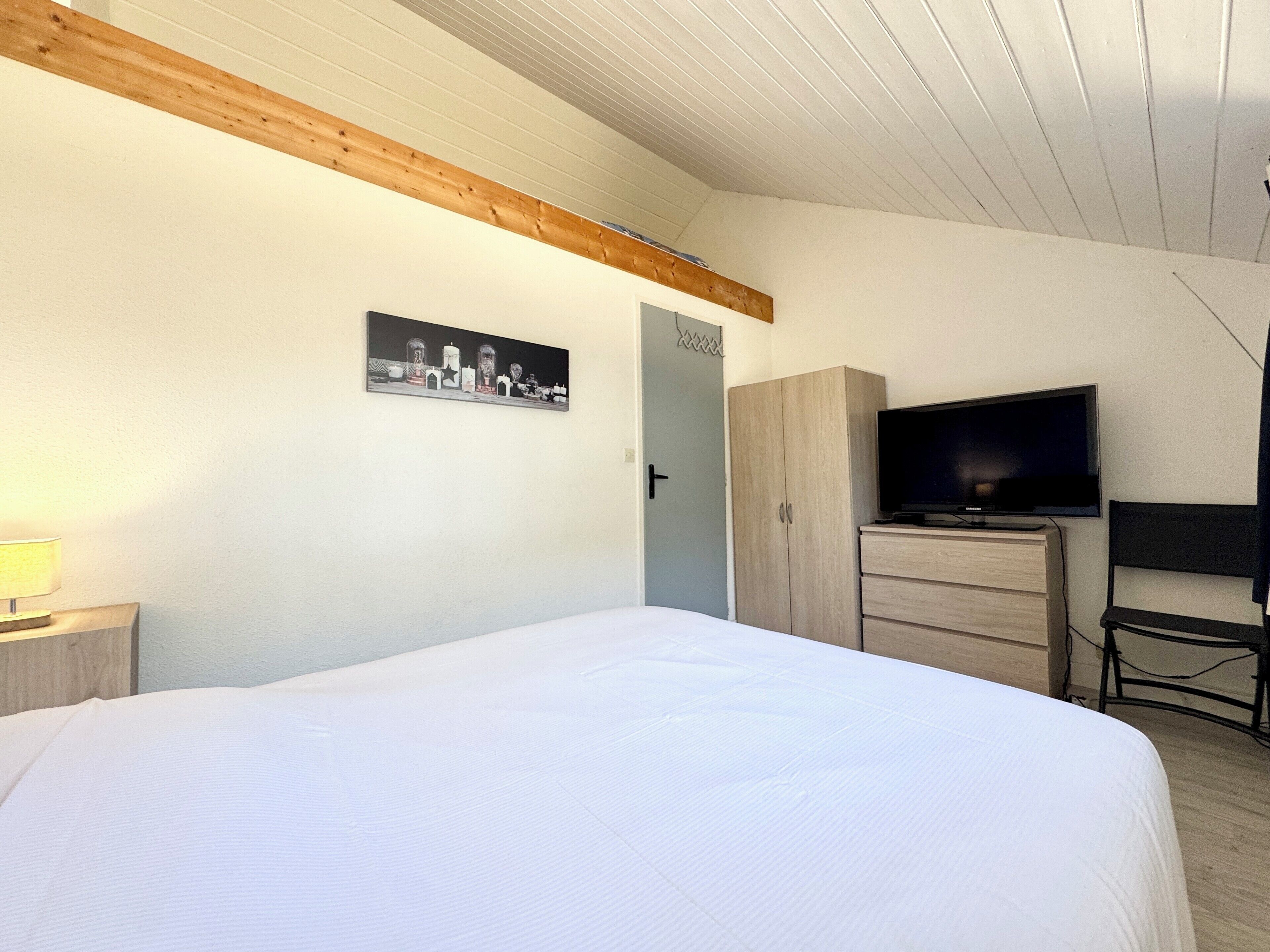 A bedroom with a bed, a television, a wardrobe, and a door.