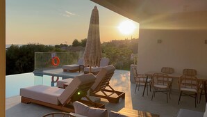 A rooftop terrace with a pool, lounge chairs, and a table with chairs. - Luxurious Villa Retreat in Lourdata (Kefalonia)
