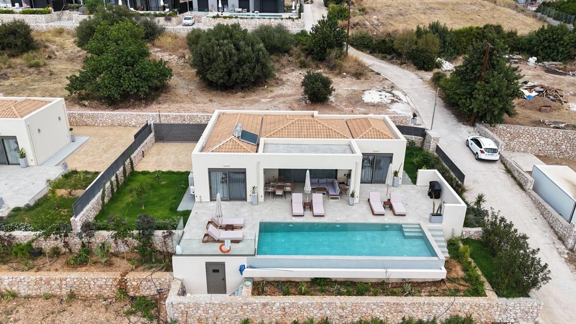 Une maison moderne à deux étages dotée d’une piscine, d’un espace de détente extérieur et d’un chemin en pierre.