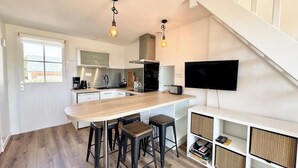 A modern kitchen with a wooden island, bar stools, a built-in TV, and a staircase. - Maison refaite à neuf - Piscine et parking privé (Guidel)