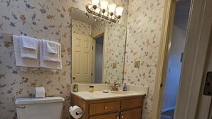 Een badkamer met toilet, wastafel en spiegel.