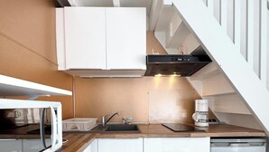 Una cocina compacta con alacenas blancas, microondas, lavamanos y lavavajillas.