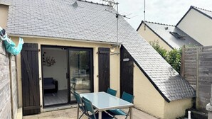 Un patio con mesa y sillas, un patio corredero de vidrio y un pequeño jardín.