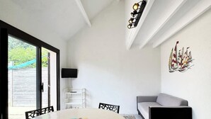 Un comedor con una mesa redonda, sillas, un sofá y una lámpara fijada a la pared.