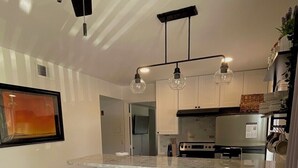 Een moderne keuken met een centraal eiland, hanglampen en een plafondventilator.