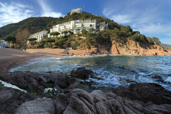 A coastal hotel with a rocky shoreline, a beach, and a hill with buildings. - 🏖Sea views + private beach. What else? (Tossa de Mar)