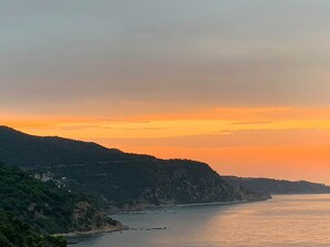 A coastal landscape with a sunset, a body of water, and a hilly terrain with buildings. - 🏖Sea views + private beach. What else? (Tossa de Mar)