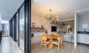 A modern dining area with a wooden table and chairs, a pendant light, and a city view through large windows. - Building With Swimming Pool Next to Balneario Shopping in BC - TSO (Balneário Camboriú)