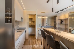 A modern kitchen with a built-in oven, a sink, and a bar area with stools. - Building With Swimming Pool Next to Balneario Shopping in BC - TSO (Balneário Camboriú)