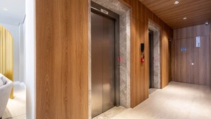 Un couloir aux murs lambrissés, un ascenseur et une pancarte indiquant « Social » sur l’ascenseur.