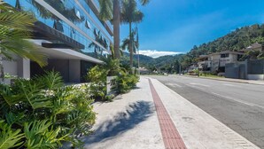 Un bâtiment moderne doté d’une façade en verre, un trottoir avec un revêtement de sol tactile et une route où circulent des véhicules.
