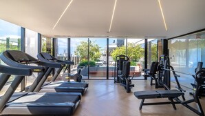 Une salle de sport équipée de tapis de course, d’appareils de musculation et d’un banc.