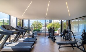 Una palestra con tapis roulant, macchinari per pesi e una panca.