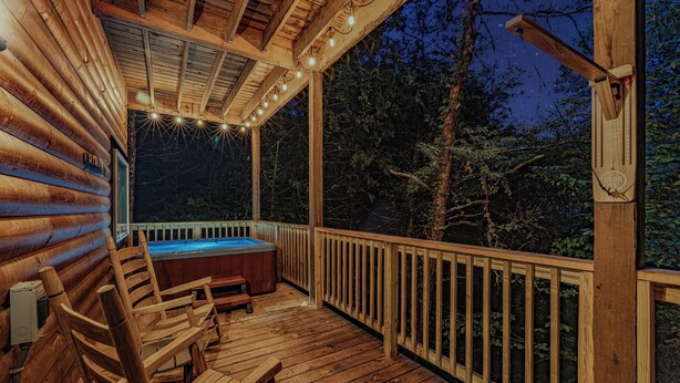 Una terraza de madera con un jacuzzi, sillas de madera y una barandilla de madera.