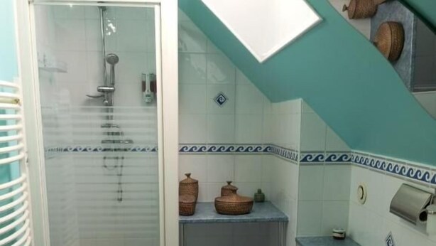 A bathroom with a glass-enclosed shower, a sink, and a vanity with cabinets. - holistica (Saint-Fargeau)