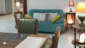 Un salon avec un canapé de couleur turquoise, une table à manger avec des chaises et deux lampes.