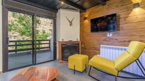 A modern living room with a fireplace, a yellow armchair, and a television mounted on a wooden wall. - Slopes 2-BR Apartment In Kfardebian Near Slopes (Kfardebian)
