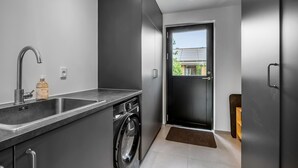 A modern kitchen with a built-in washing machine, a sink, and a door leading to a balcony.