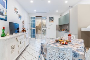 Une cuisine moderne avec un coin repas, des meubles blancs et un téléviseur.