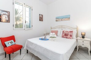 A neatly arranged bedroom with a bed, a chair, a bedside table, and a window.