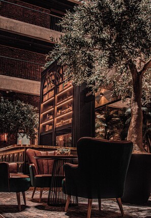 Una biblioteca con estanterías, sillones de cuero y un árbol grande.