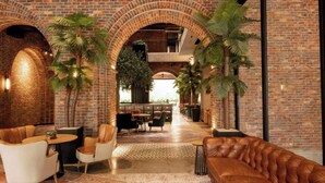 Um hall amplo com arcos de tijolo, assentos de couro e uma planta central.