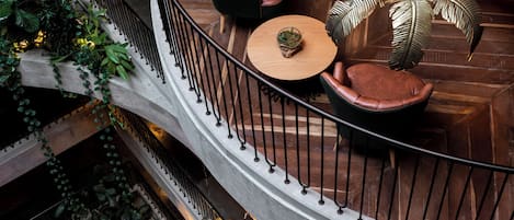A multi-level interior with a central spiral staircase, seating areas with leather sofas, and decorative leaf-patterned lighting fixtures.