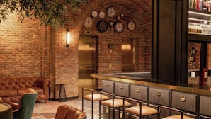 Uma área de bar com parede de tijolos, relógios, balcão e assentos.