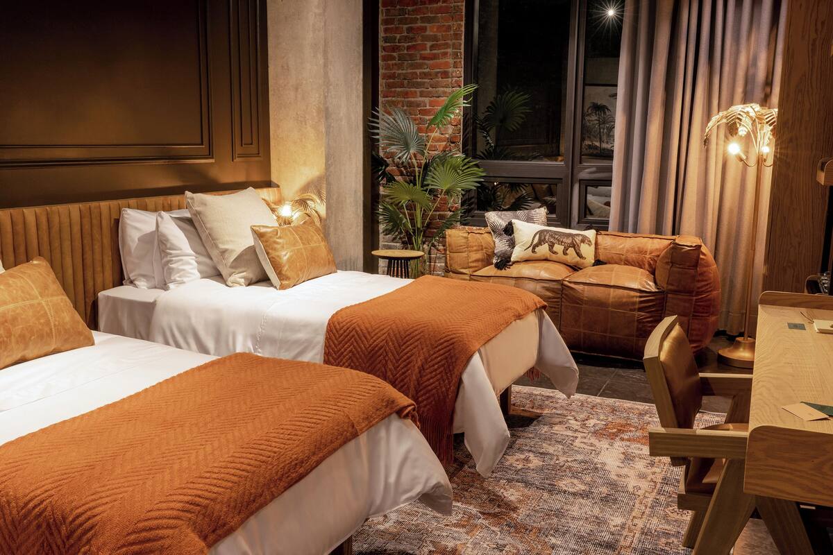 Een hotelkamer met twee bedden, een houten eettafel en uitzicht op de nachthemel.