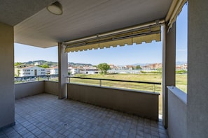 Un balcon avec un sol carrelé, une vue sur le paysage urbain et une balustrade.