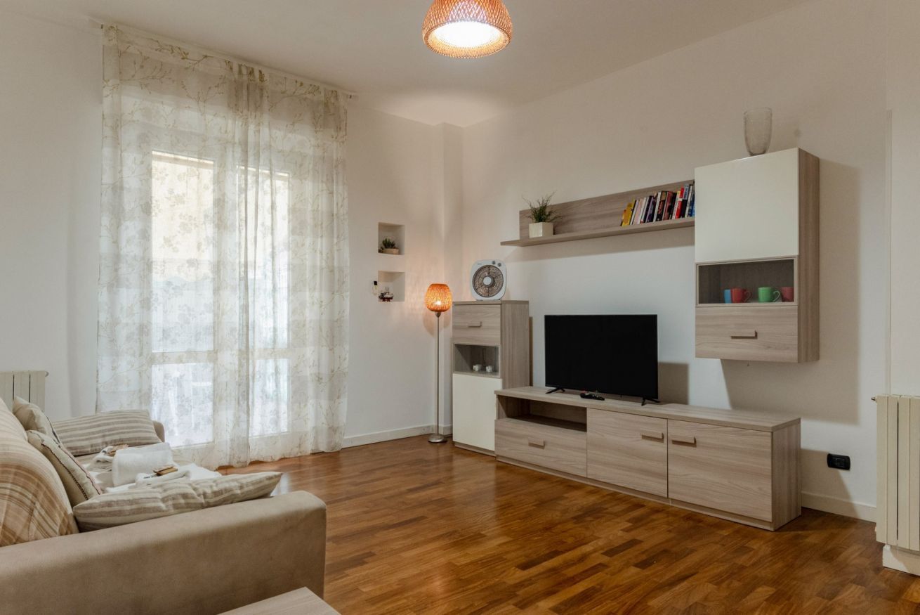 Un salon comprenant un canapé, un téléviseur, un meuble en bois et un lampadaire.