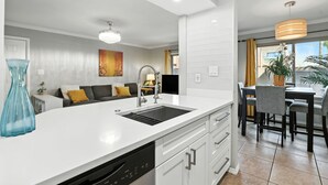 A modern kitchen with white cabinetry, a built-in dishwasher, and a large island with a sink. - Golf Course remodeled main floor condo in Old Town Scottsdale with King beds (Scottsdale)