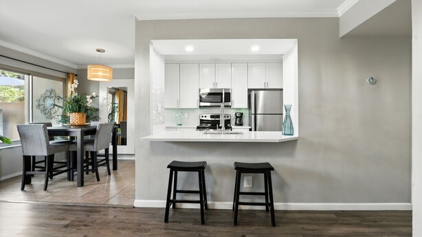 A modern kitchen with white cabinets, stainless steel appliances, and a central island with stools. - Golf Course remodeled main floor condo in Old Town Scottsdale with King beds (Scottsdale)