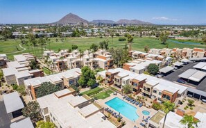 Een resort met meerdere gebouwen, een zwembad en een golfbaan op de achtergrond.
