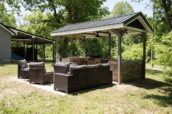 An outdoor patio with wicker furniture and a barbecue area.