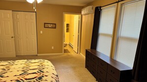 A bedroom with a bed, dresser, and a walk-in closet.