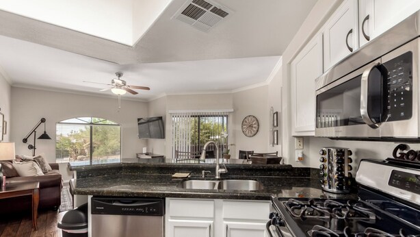 A modern kitchen with a dishwasher, stove, microwave, and a large window overlooking a garden.