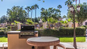 An outdoor patio area with a barbecue grill and a round table.