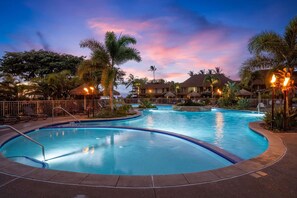 A pool area with multiple swimming pools, lounge chairs, and palm trees.