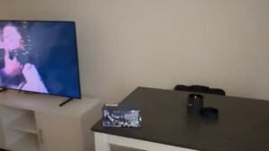 Habitació amb televisió sobre un prestatge, una taula amb una cadira i un parell de xapes a terra.