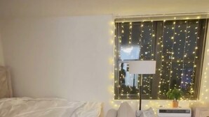 Un dormitori amb un llit, un sofà i una tauleta de nit amb una làmpada.