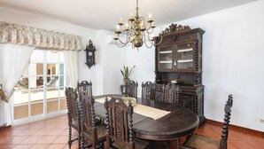 Ein Esszimmer mit einem runden Tisch, verzierten Stühlen, einer Kandelaber und einer großen Holzvitrine.