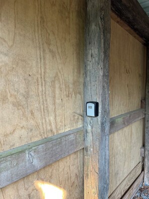 A wooden door with a security keypad, a wooden beam, and a metal latch. - Charming house with beautiful views (Gedser)